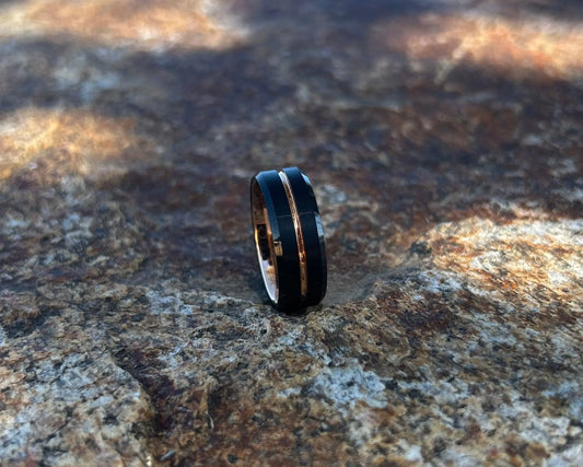 Black & rose gold inlay ring on a textured rock