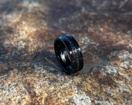 Black ring with black CZ's on a textured stone surface