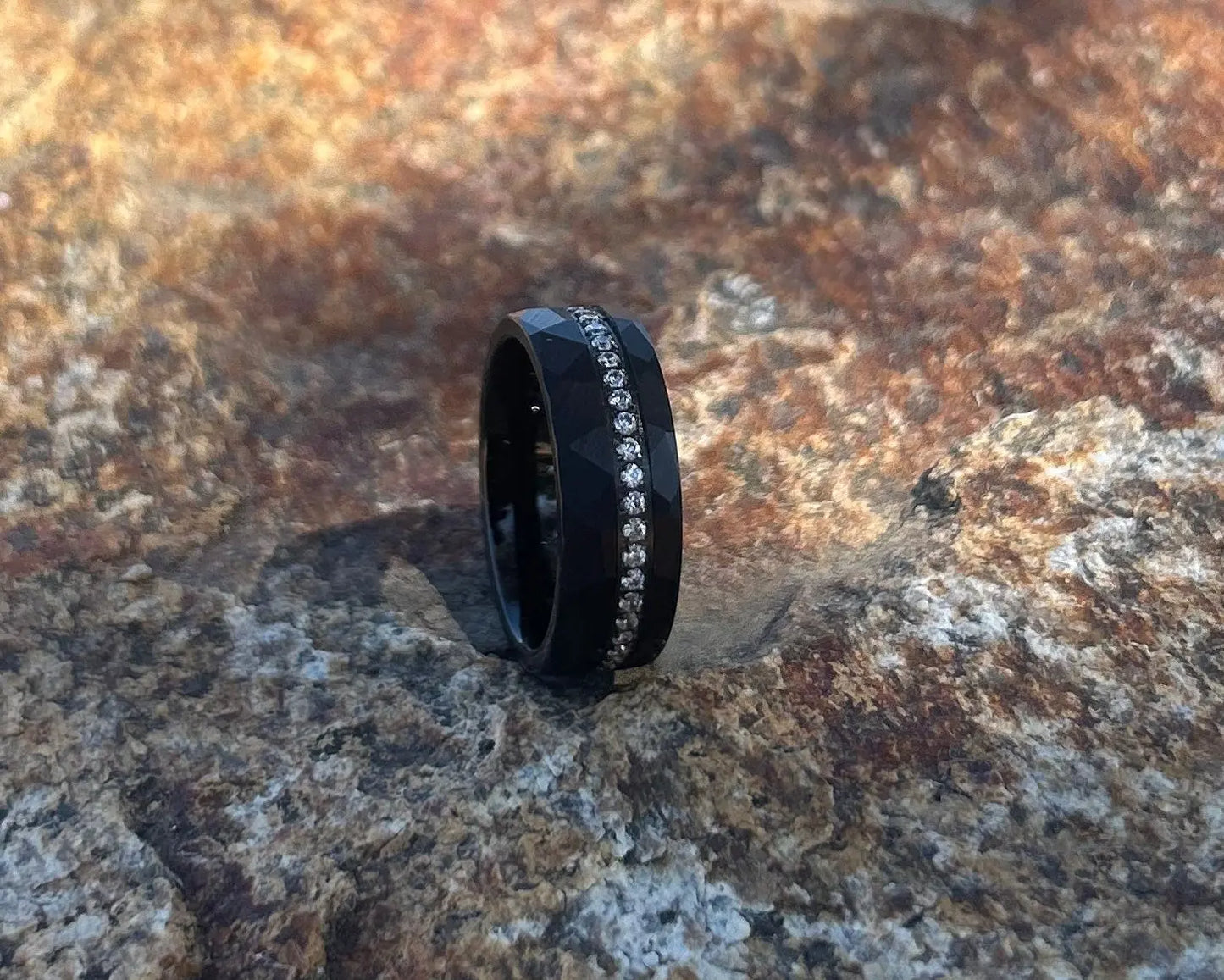 Black ring with embedded stones on a textured stone surface
