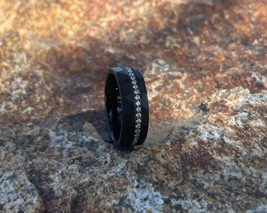 Black ring with embedded stones on a textured stone surface