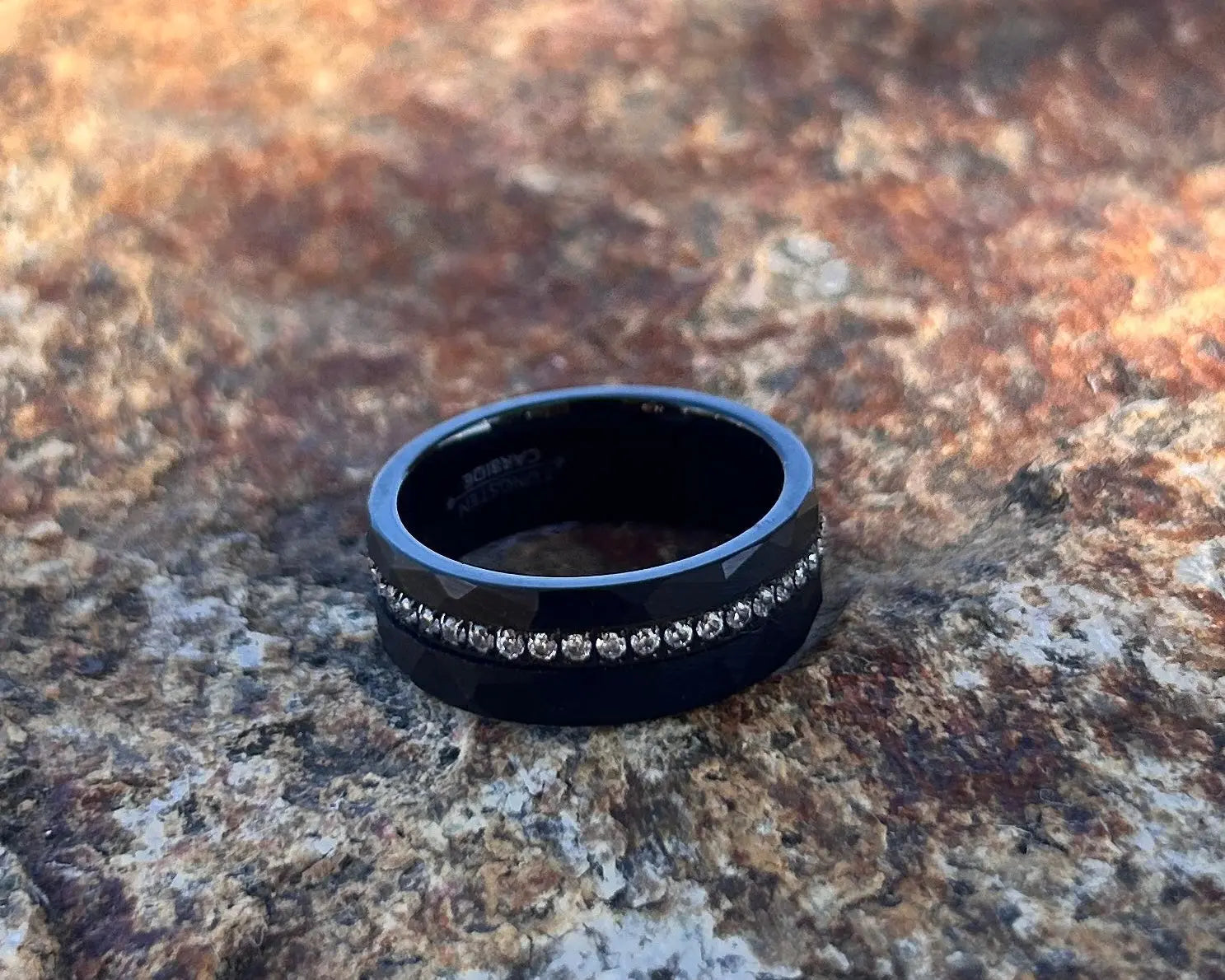 Black ring with embedded stones on a textured stone surface