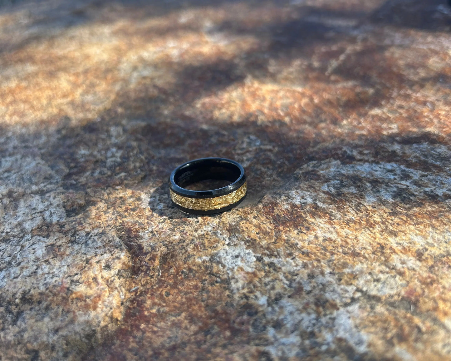 Black ring with gold inlay on a textured stone
