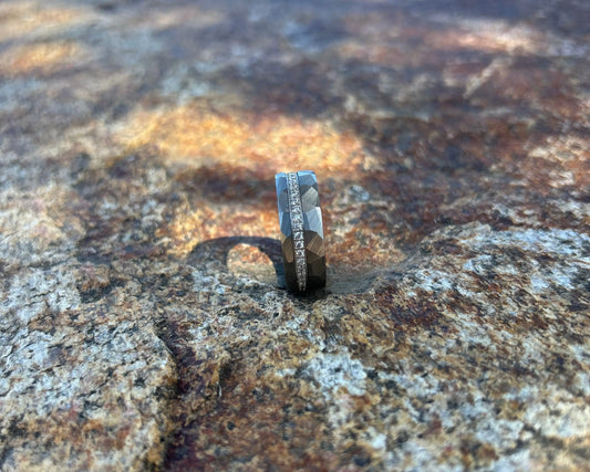 Silver ring with CZ's and hammer accents on a textured rock surface