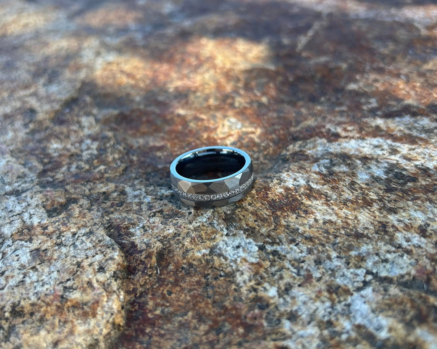 Silver ring with CZ's interior hammered design on a textured stone surface