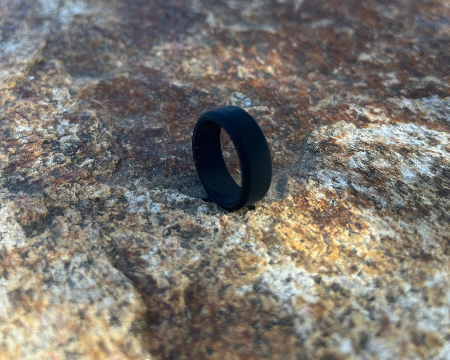 Black silicone ring on a textured stone surface.
