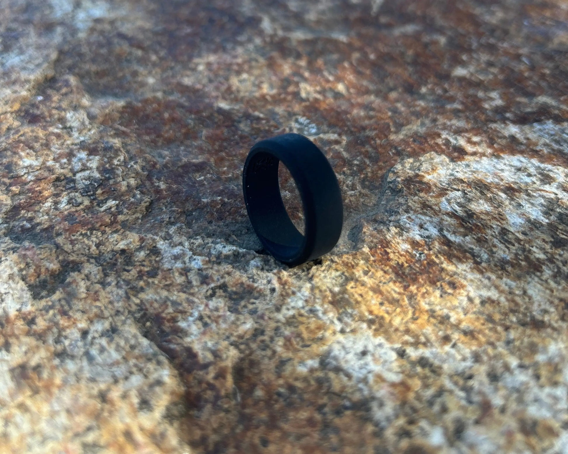 Black silicone ring on a textured stone surface.