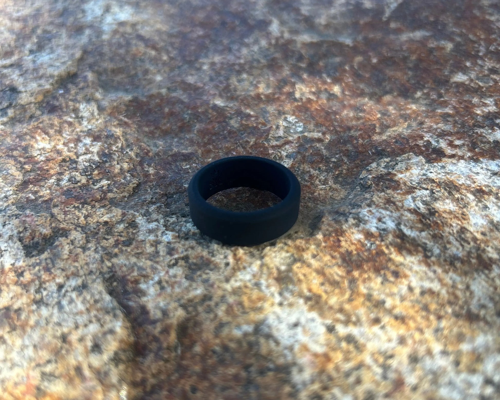 Black silicone band resting on textured stone.