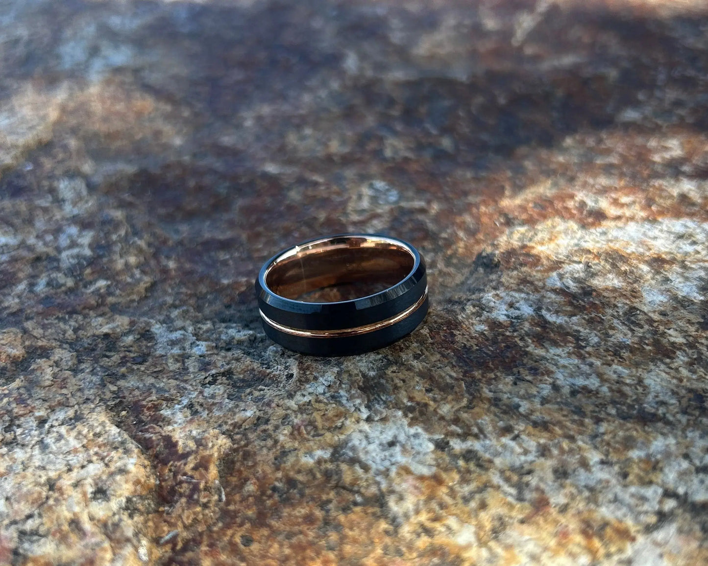 Black rose gold inlay ring on a textured rock
