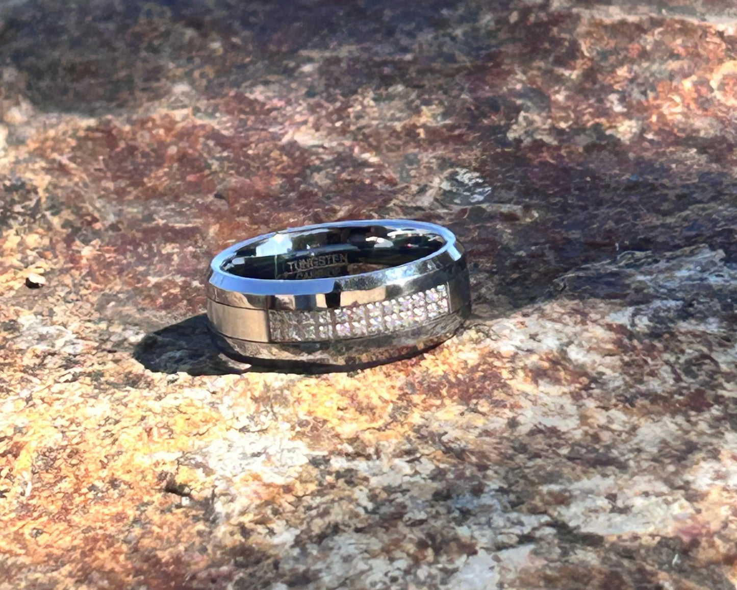 Silver ring with black accents on a textured brown surface