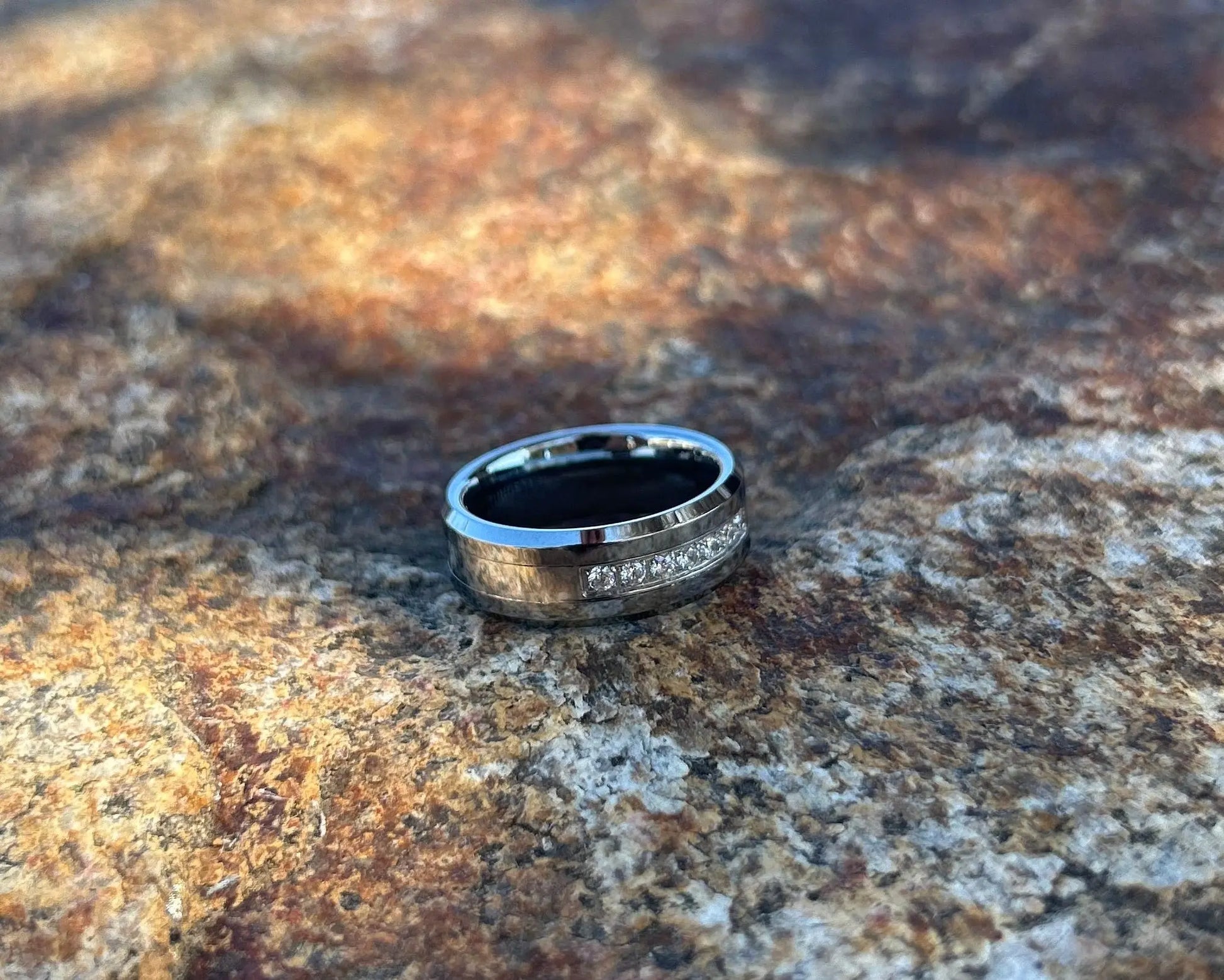 Silver ring with CZ channel on a textured stone surface