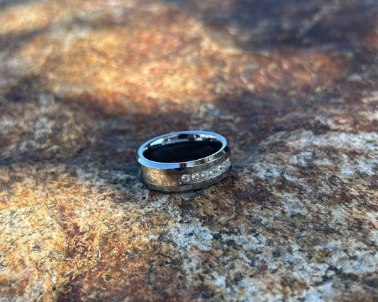 Silver ring with CZ channel on a textured stone surface
