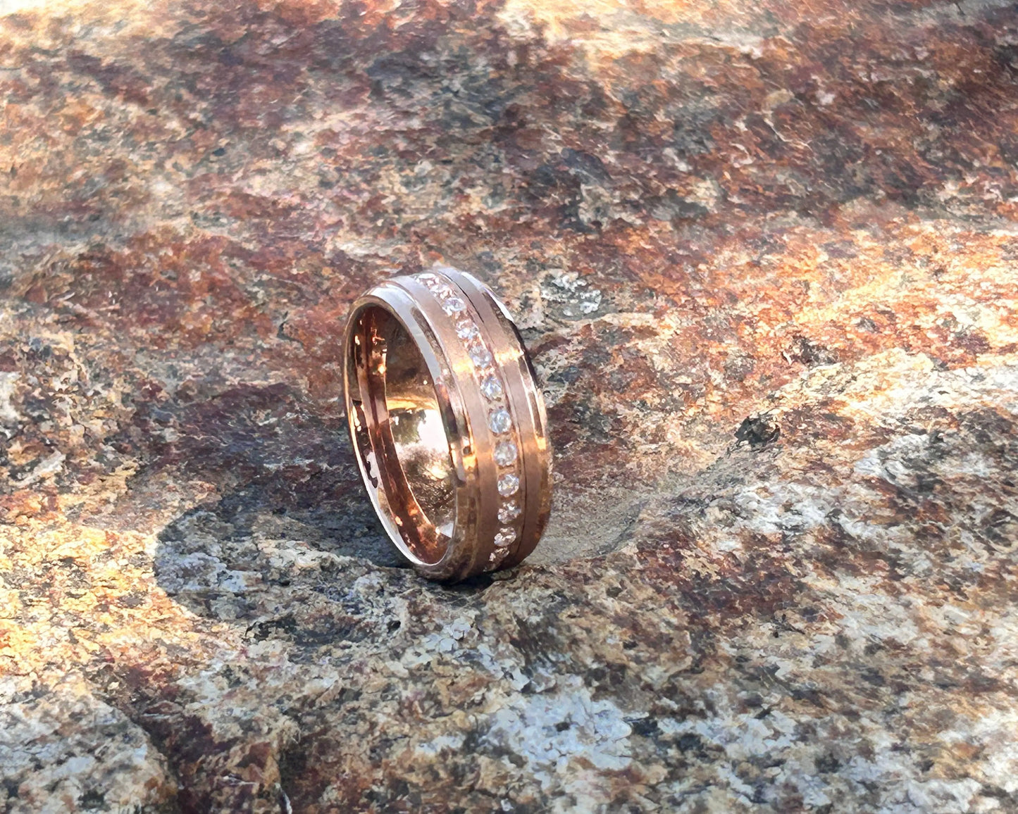 Gold ring with engraved text on a textured stone surface