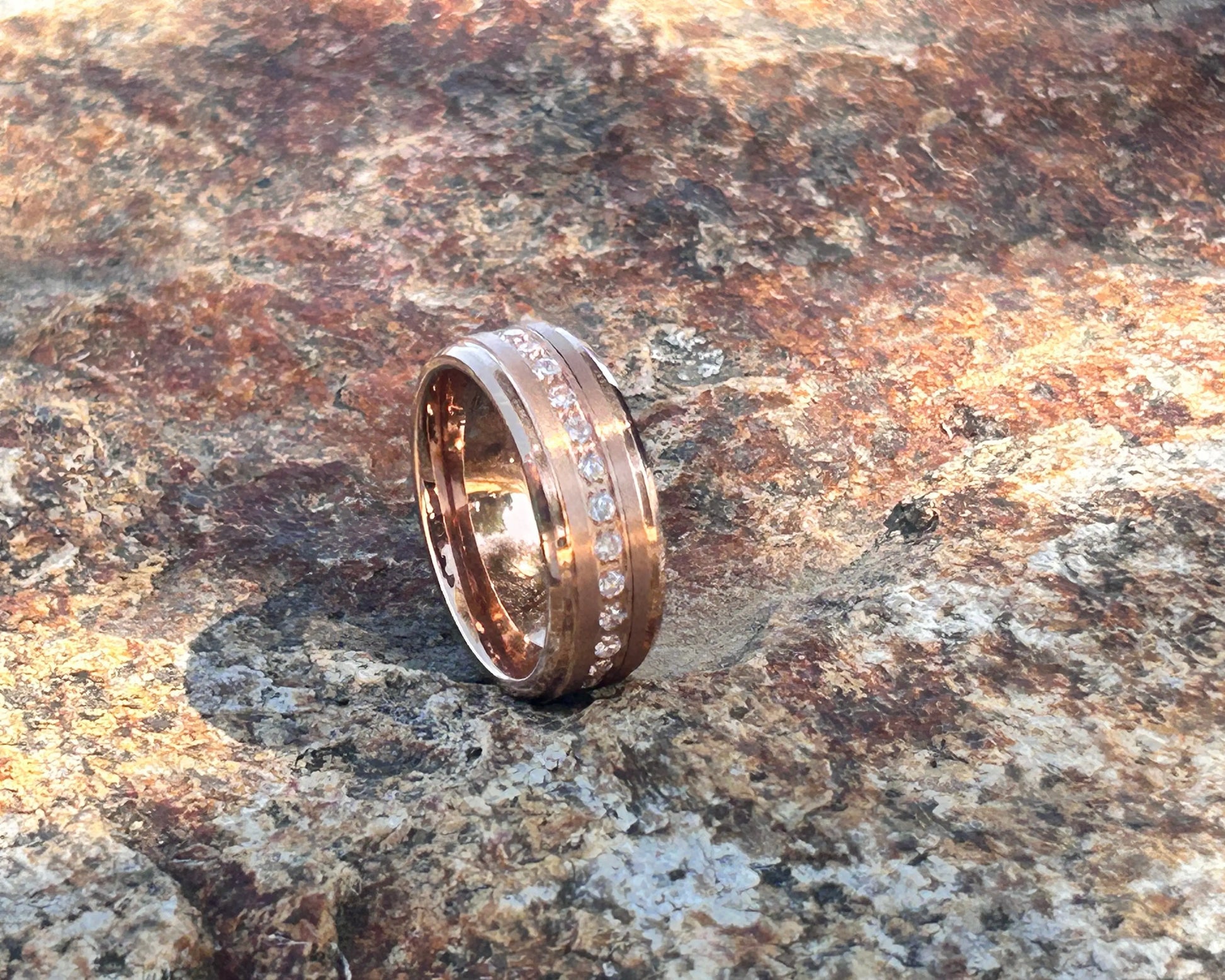 Gold ring with engraved text on a textured stone surface