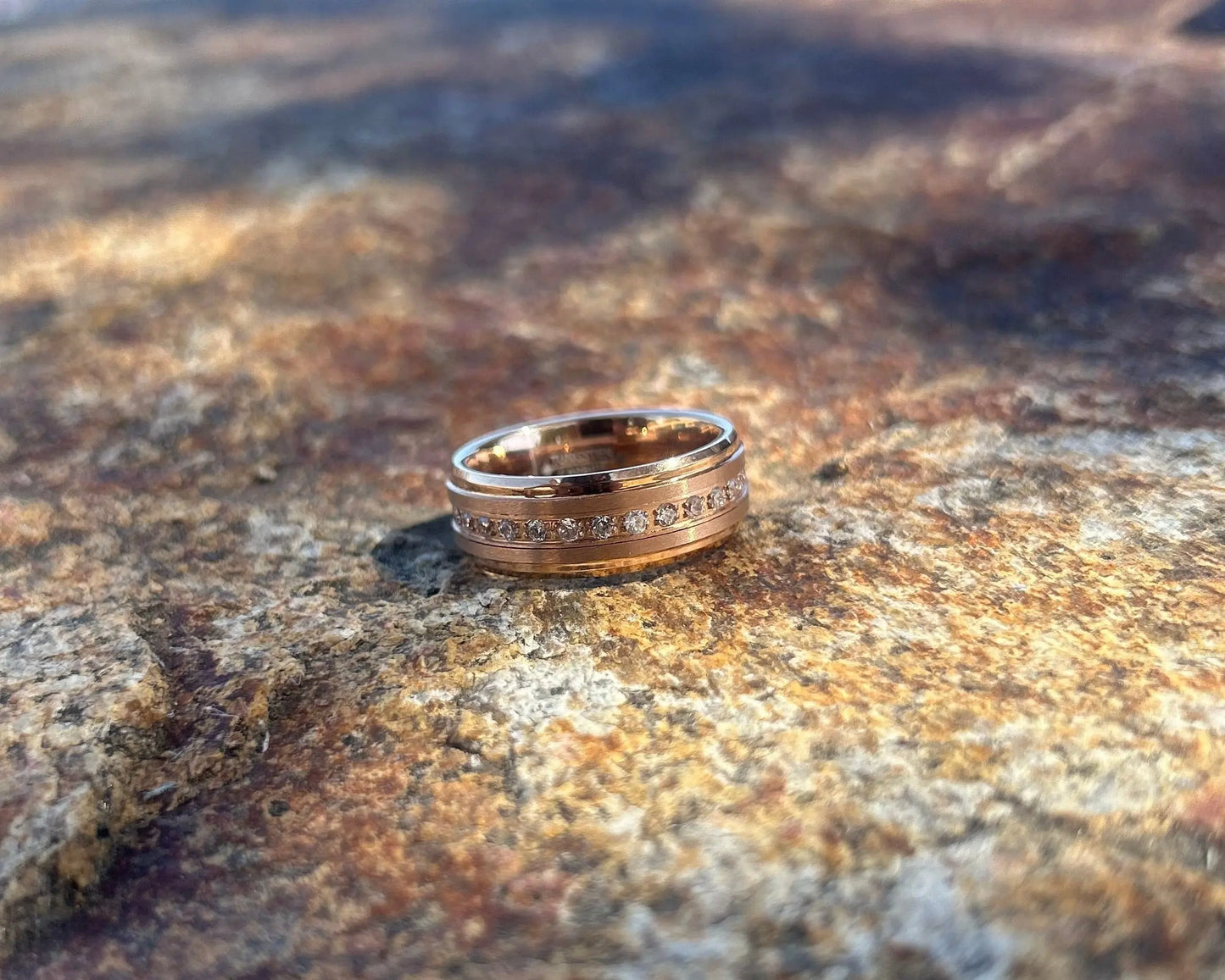 Gold ring on a textured stone surface with a blurred natural background
