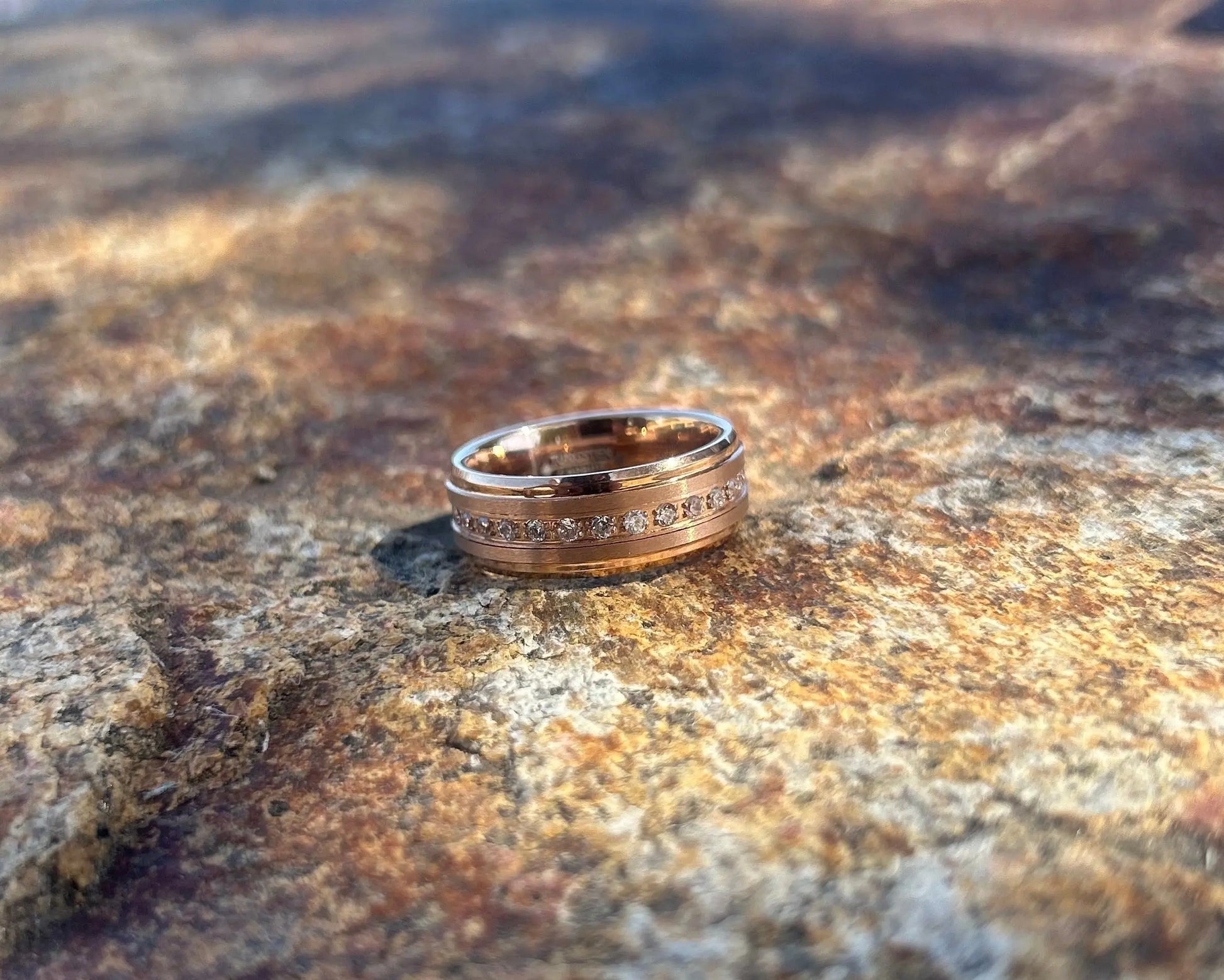 Gold ring on a textured stone surface with a blurred natural background