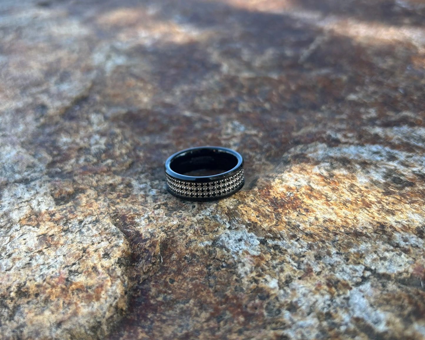 Black ring with rows of CZ stones on a textured rock