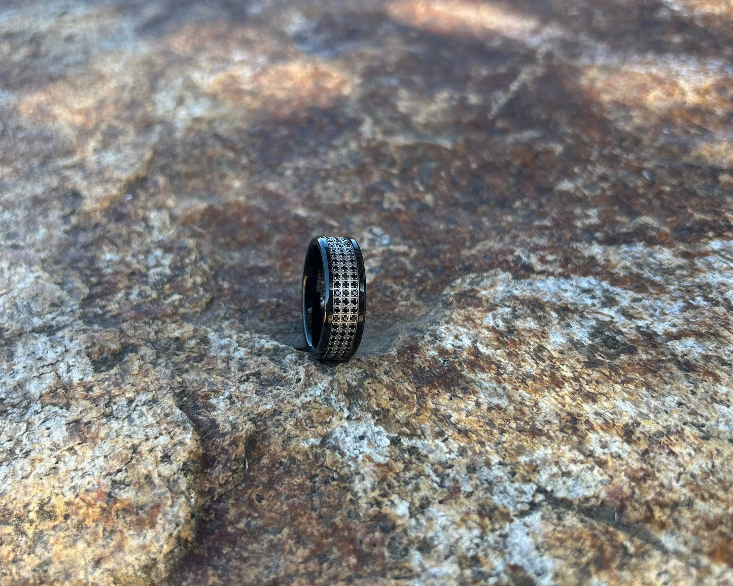 Black ring with rows of CZ stones on a textured rock