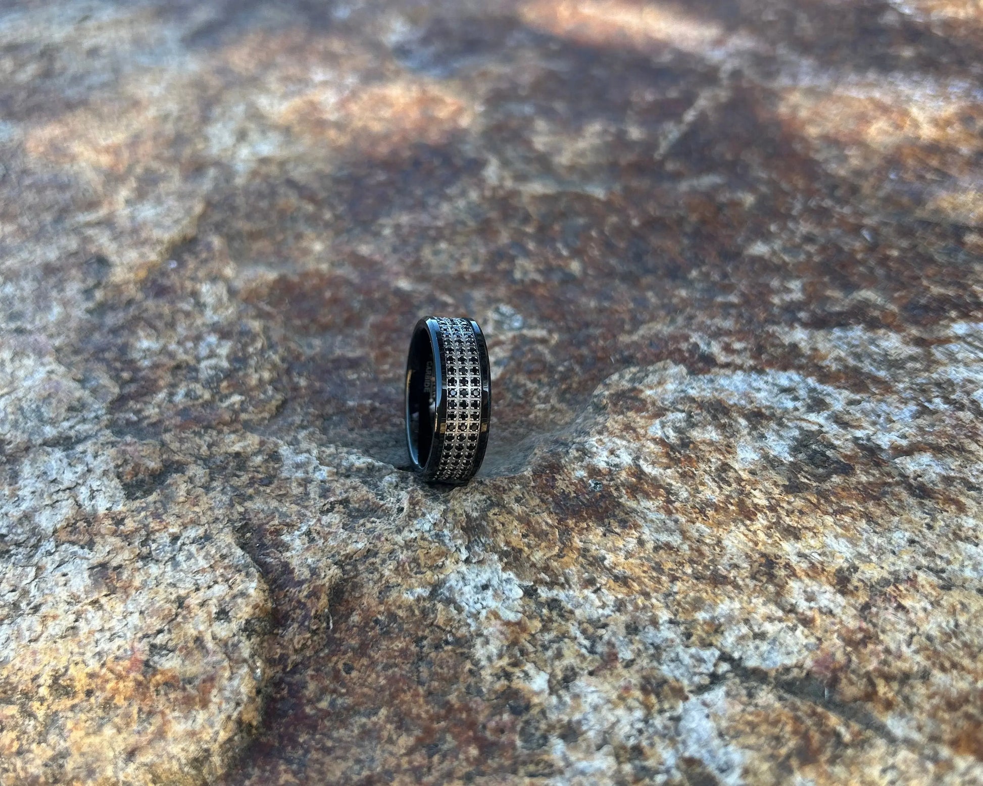 Black ring with rows of CZ stones on a textured rock