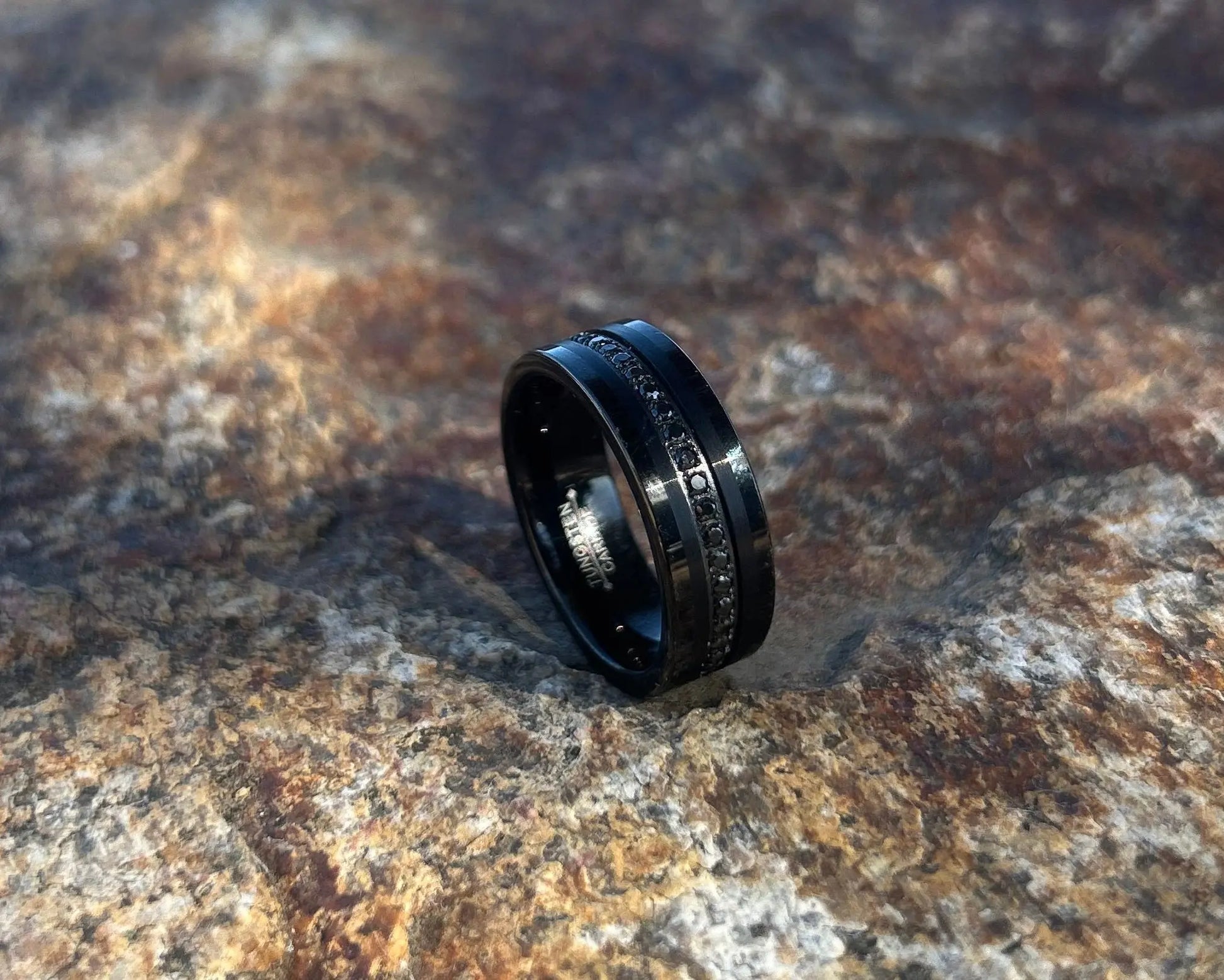 Black ring with black CZ's on a textured stone surface