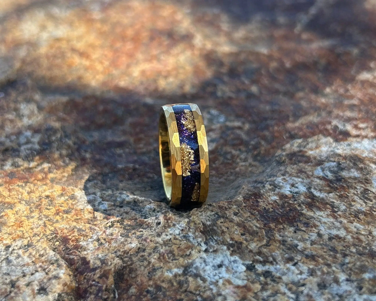 Gold ring with blue & gold stardust inlay on a textured rock