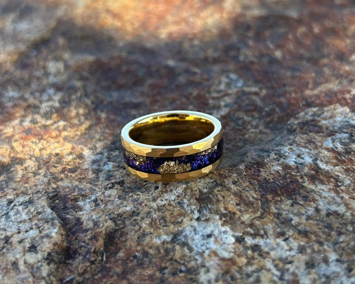 Gold ring with blue & gold stardust inlay on a textured rock