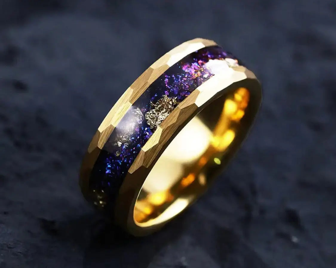 Gold ring with blue & gold stardust inlay on a dark surface